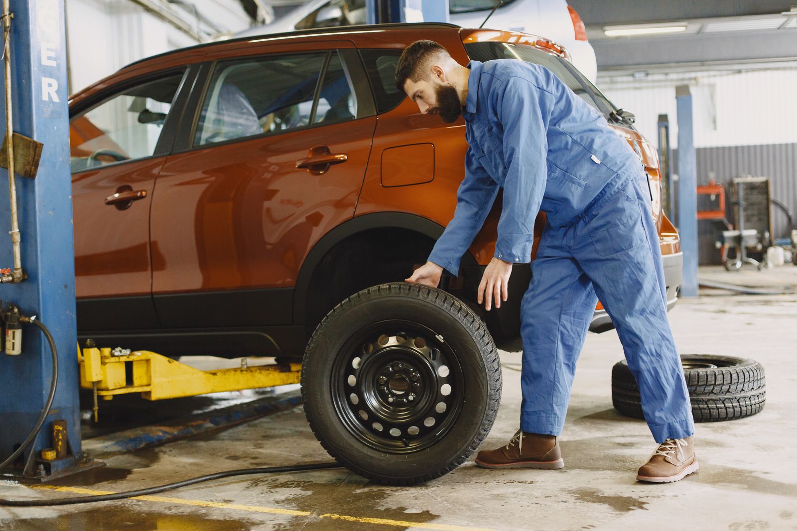 Mechanic fitting a wheel onto an SUV on a shop jack