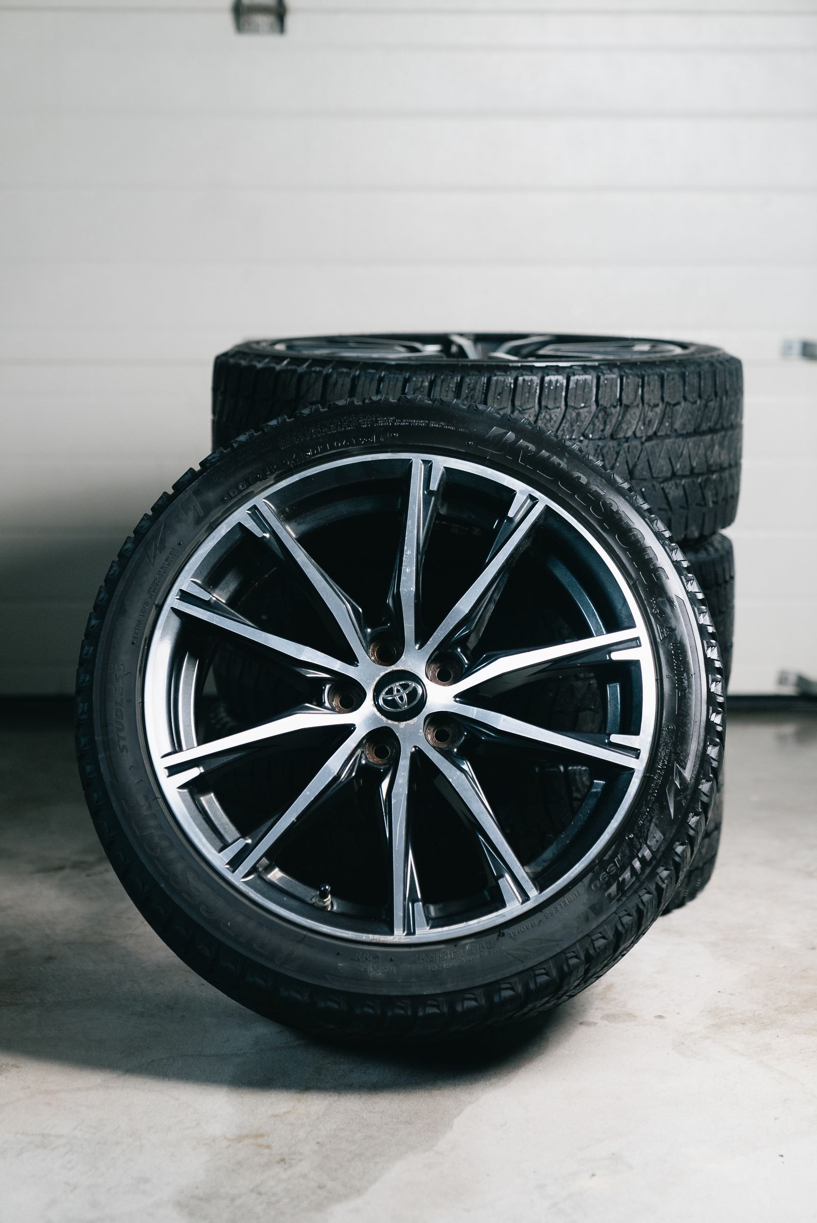 New tires stacked with an alloy wheel in a garage