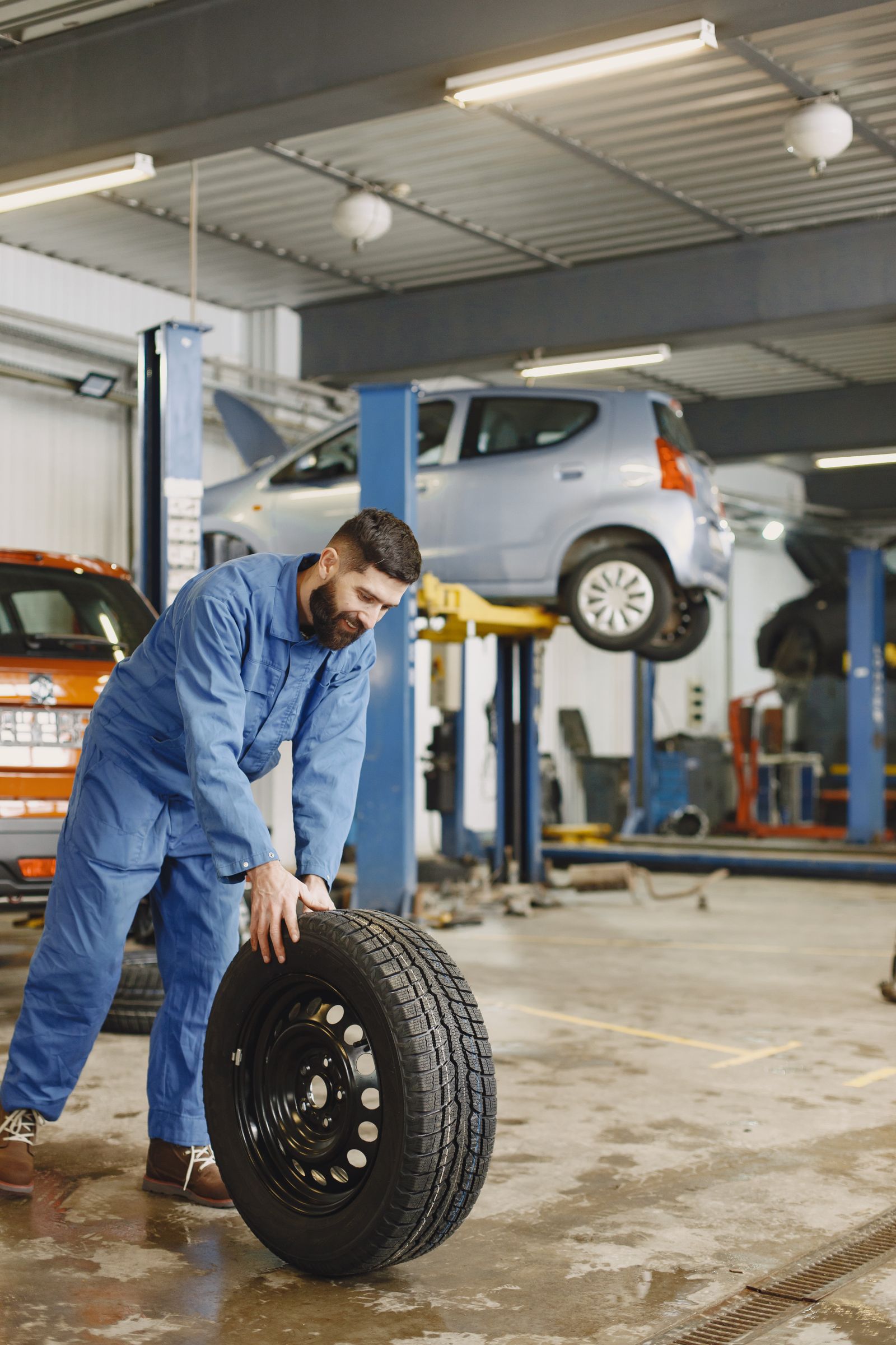 Mechanic rolling a tire across the shop floor